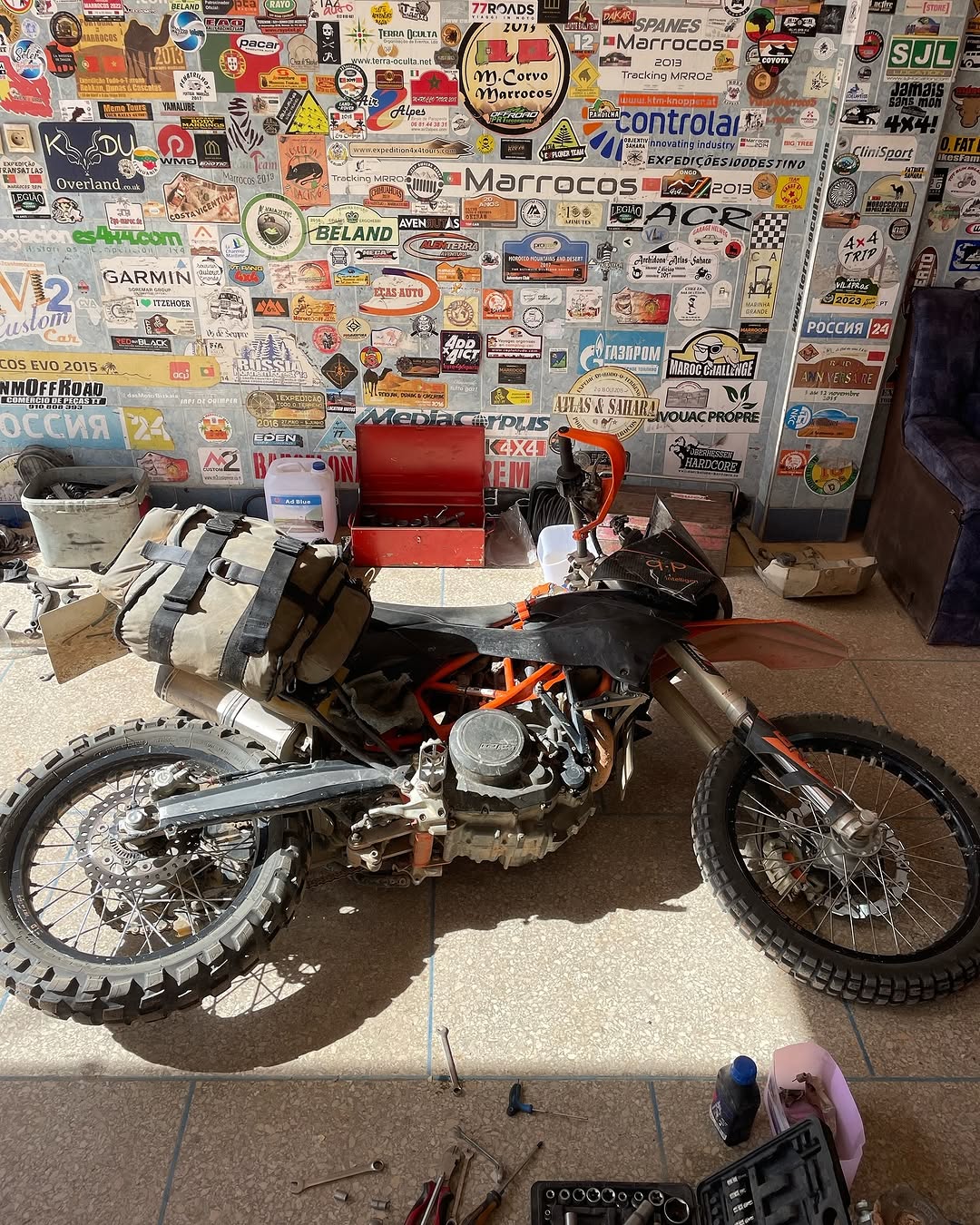 Loaded orange KTM enduro bike on the workshop floor at Garage Iriki Zagora, ready for a clutch swap after a desert breakdown