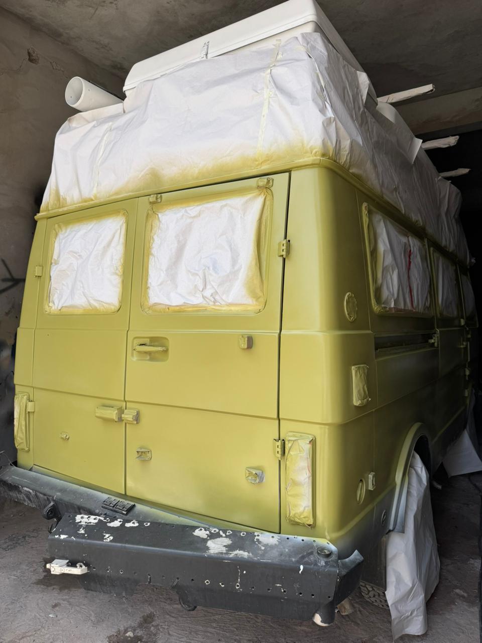 Freshly sprayed yellow-green rear of the VW camper still masked at the roof, before unmasking and reassembly