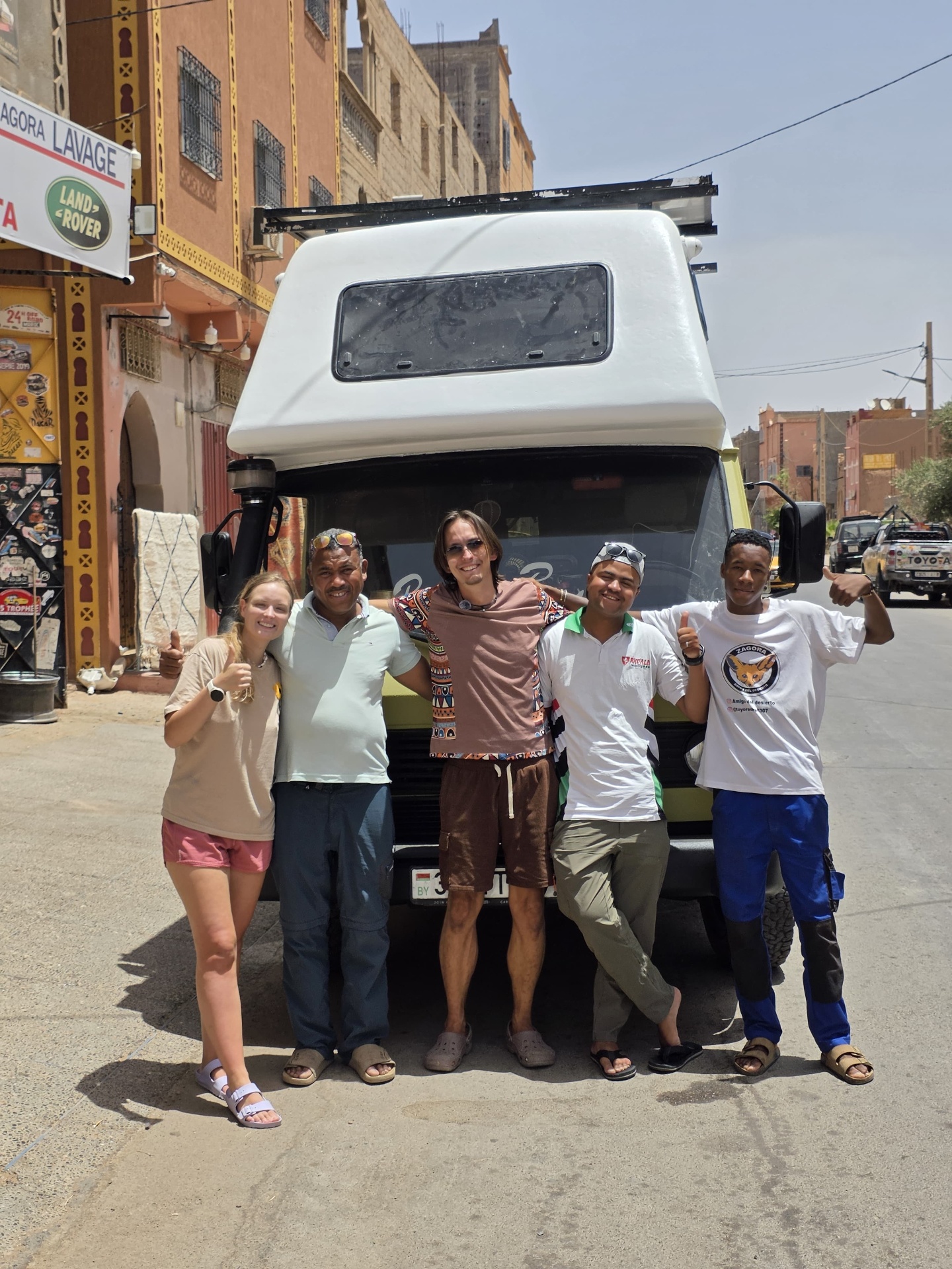 Team photo in front of the finished green and white Belarusian VW camper on the street in Zagora after the full repaint at Garage Iriki