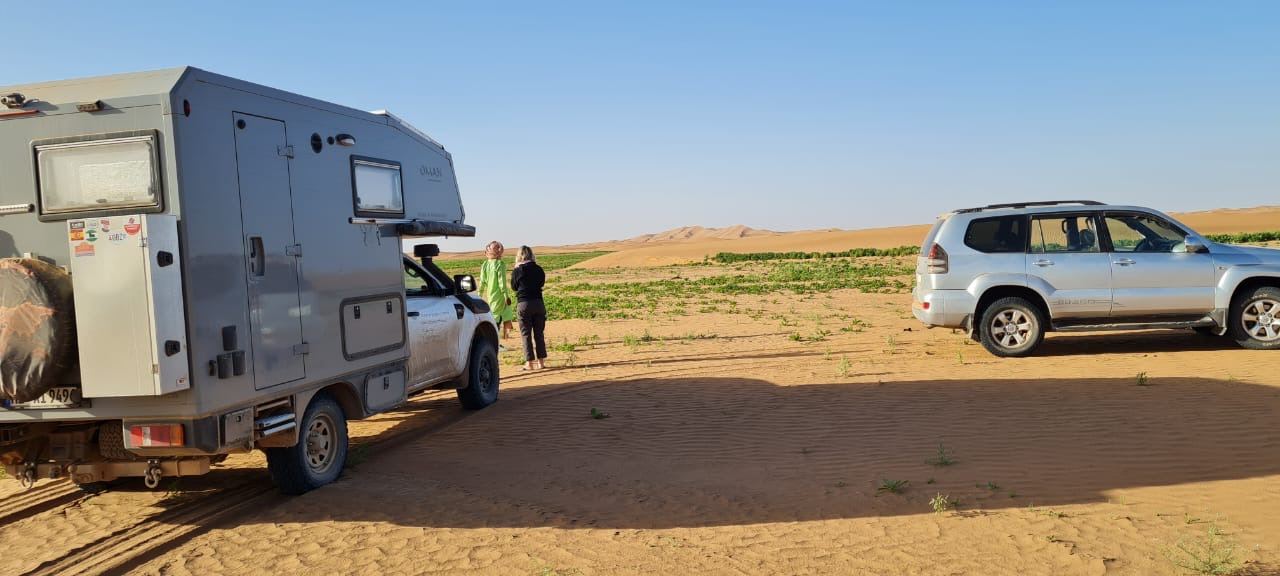 Expedition camper and silver SUV on the dunes
