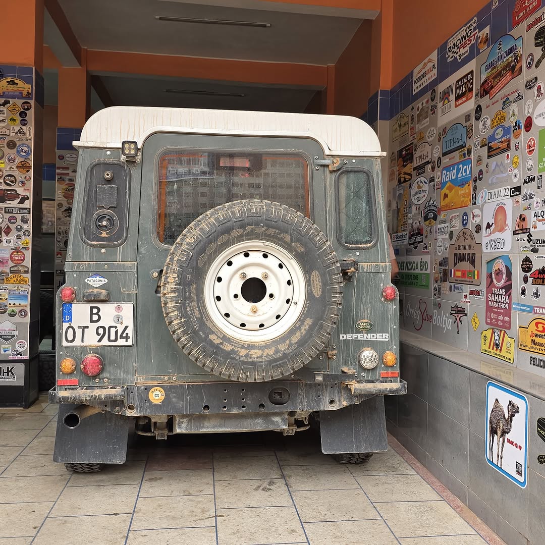 Rear view of the German Land Rover Defender B-OT 904 back on its wheels in front of the Garage Iriki sticker wall
