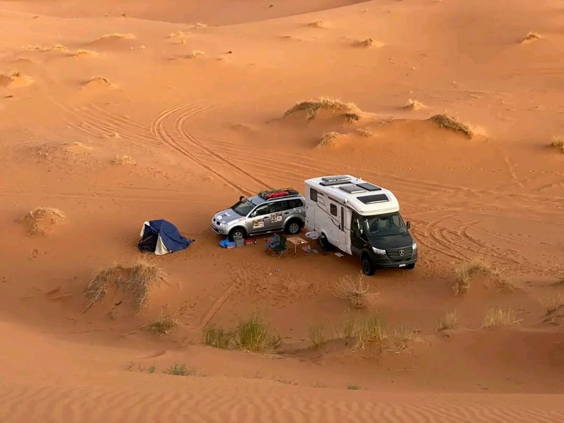 Camp and vehicles at the edge of the dunes