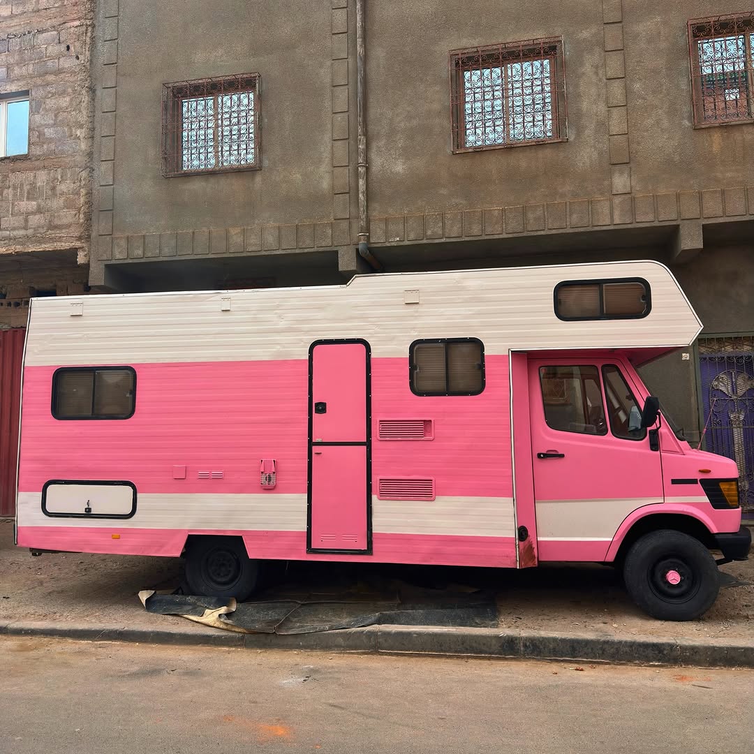 Full side view of the raised pink Mercedes 407D overland camper in southern Morocco