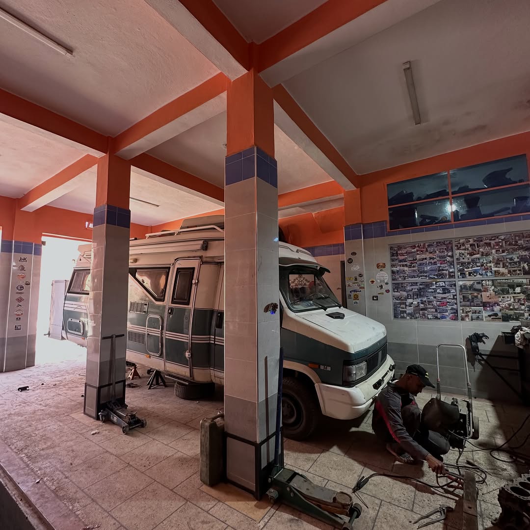 Zicaaaas mechanic working under the Austrian camper van in Garage Iriki workshop in Zagora, Morocco